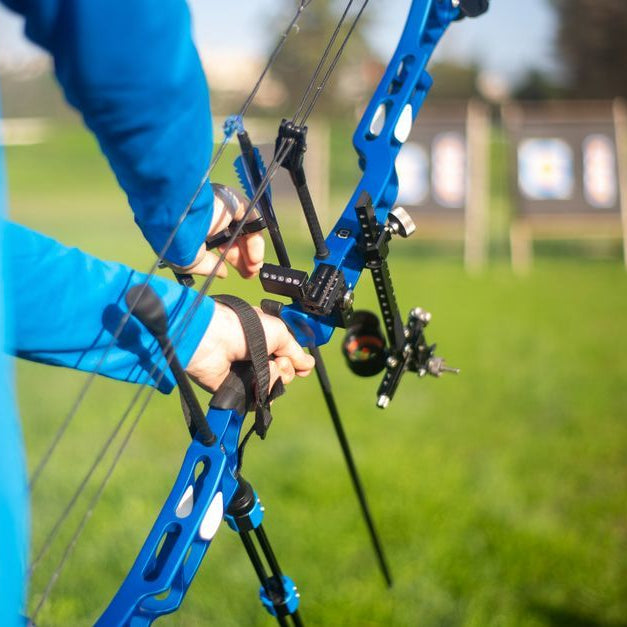 Person aiming blue compound bow at targets