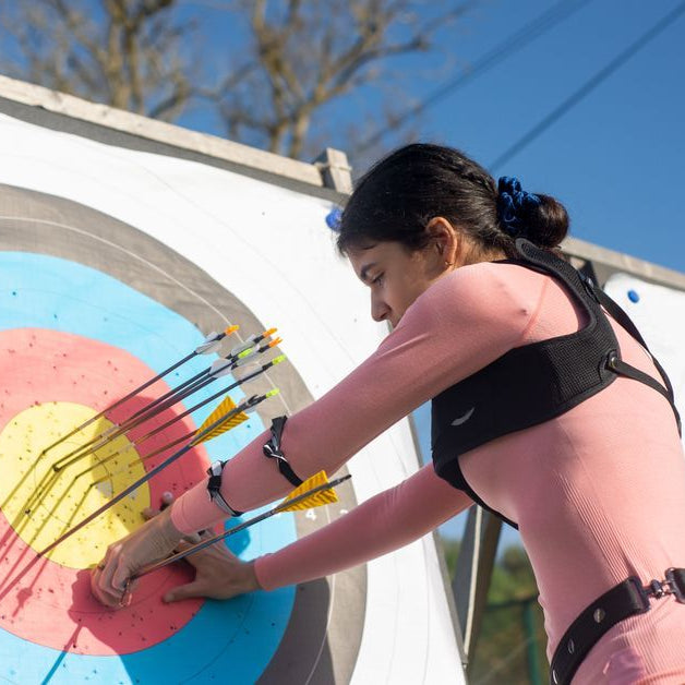 Woman pulling arrows from colorful archery target