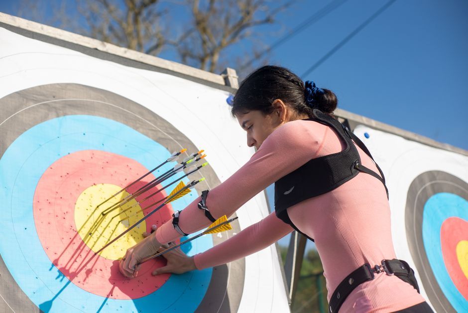 Woman pulling arrows from colorful archery target